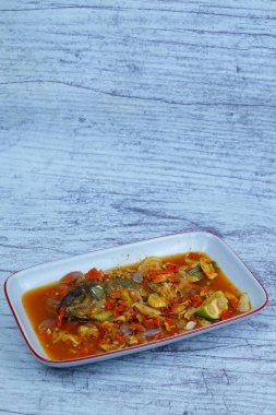 Pecak Ikan Mujair ya da kızarmış tilapia canlı, baharatlı ve ekşi Endonezya biberine batırılmış soğan ve kireç ile birlikte beyaz bir tabakta servis edilir..