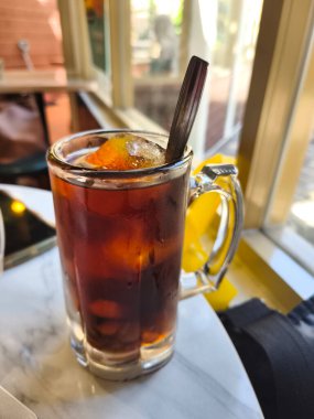 Lo Han Kuo ya da Monk Fruit İçeceği, koyu kehribar rengi ve kaşık, güneşli bir pencere tarafından hazırlanmış buzlu bir içecek..