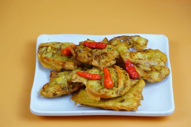 Kırmızı biberli Endonezya usulü kızarmış sebze ya da bakwan tabağı, turuncu arka planda..