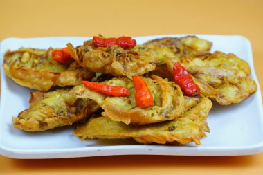 Kırmızı biberli Endonezya usulü kızarmış sebze ya da bakwan tabağı, turuncu arka planda..