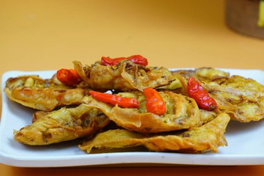 Kırmızı biberli Endonezya usulü kızarmış sebze ya da bakwan tabağı, turuncu arka planda..