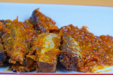 Dikdörtgen beyaz tabakta sambal balado ya da sade sarı bir zemin üzerine kurulmuş zengin baharatlı acı biber soslu birkaç parça kızarmış Mackarel ton balığı bulunur..