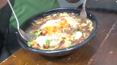 El sıcak ançüezli vermicelli karıştırıyor. Singkawang, Endonezya 'nın spesiyali. Sıcak et suyu gözle görülür şekilde buharlaşıyor..
