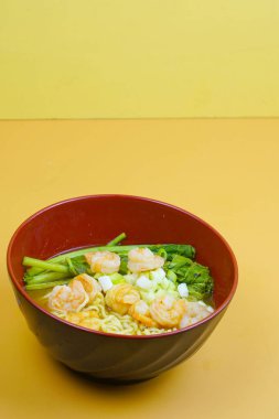 İçinde şehriye, sulu karides, gevrek yeşil sebzeler ve lezzetli bir çorbanın içinde doğranmış yeşil soğan olan canlı bir kase ramen..