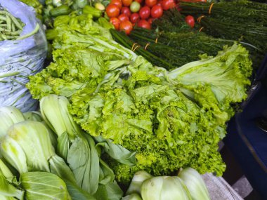 Canlı bir market, yapraklı yeşiller, domatesler ve fasulyeler de dahil olmak üzere taze sebzelerle dolup taşıyor..