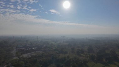 Ağaçlarla çevrili, güneşli bir günde arabaları ve motosikletleri olan geniş, çok şeritli bir yolun hava manzarası..