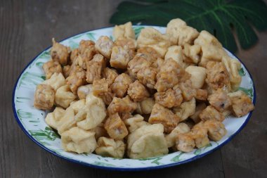 Bir tabak kızarmış tofu ve ahşap masada tempeh..