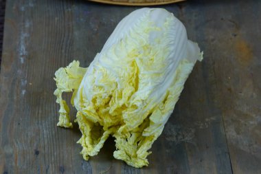 Taze bir Napa lahanası taşralı ahşap bir masada duruyor..