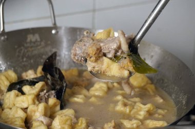 Bir metal tava lezzetli bir güveç yapar. Yanında kızarmış tofu parçaları ve metal bir kaşıkla karıştırılmış tavuk gibi görünen bir şey..