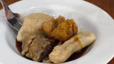 Lezzetli bir tabak pempek, lezzetli bir Endonezya balık keki servis ediliyor. Pempek, Cuko adı verilen ve doğranmış salatalıkla kaplıdır..