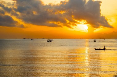 Sakin şafak deniz manzarası. Denizin üzerinde güzel bir gün doğumu, geleneksel balıkçı teknelerinin ilk ışığa yetişmesi..