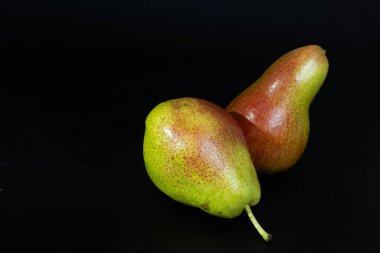 Renkli Forelle armutları koyu bir zemin üzerinde parlıyor, benekli derilerini ve taze cazibelerini vurguluyorlar..