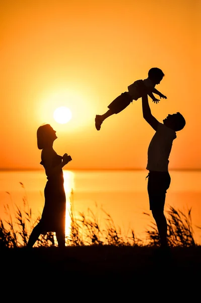 夕日を背景に 幸せな家族 母と父のシルエット 父の日の背景オレンジ日没時の海 — ストック写真