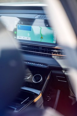 Navigasyon ekranlı araç paneli, rota haritasını gösteriyor. Modern iç mekan, yakın çekim, gün ışığı. Teknoloji ve yolculuk temaları için.