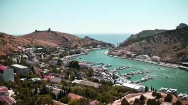 Vadideki sahil kasabasının panoramik manzarası. Arka planda marina ve deniz var. Güneşli bir günde yüksek bir açıdan çekilmiş. Kamera düzgün çalışıyor, kasabanın yerleşimini ve çevresini gösteriyor..