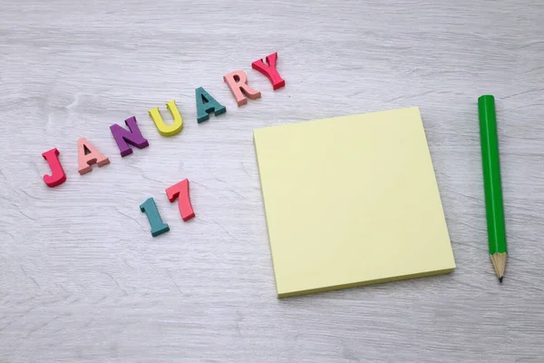 stock image January  17 - Daily colorful Calendar with Block Notes and Pencil on wood table background, empty space for your text or design 