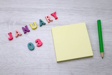 Ocak 03 - Tahta masa zemininde Blok Notlar ve Kalem içeren Günlük Renkli Takvim, metin veya tasarım için boş alan 