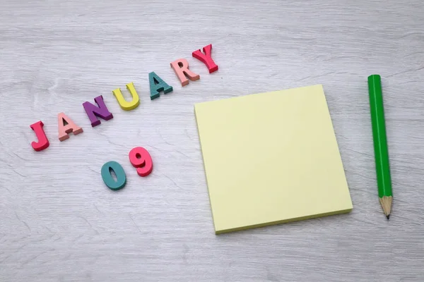 stock image January  09 - Daily colorful Calendar with Block Notes and Pencil on wood table background, empty space for your text or design 
