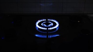 Gaz ocağı ve yanan gaz alevleri. Mavi alevleri yanan ev mutfağı