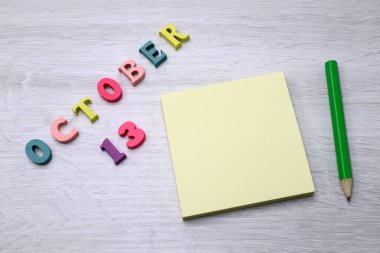 13 Ekim - Tahta masa zemininde Blok Notlar ve Kalem içeren Günlük Renkli Takvim, metin veya tasarım için boş alan