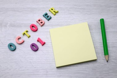 1 Ekim - Tahta masa zemininde Blok Notları ve Kalem içeren Günlük Renkli Takvim, metin veya tasarım için boş alan