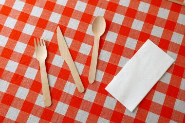 Tahta bıçak, kaşık, çatal üzerindeki kareli masa örtüsü. 