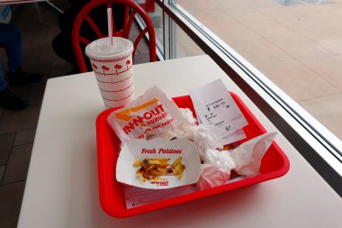 Glendale, California, ABD - 19 Mayıs 2023 - In-N-Out Burger - Hamburger ve patates kızartması fast-food restoranının içindeki masada bir tepside yemeyi bitirdikten sonra