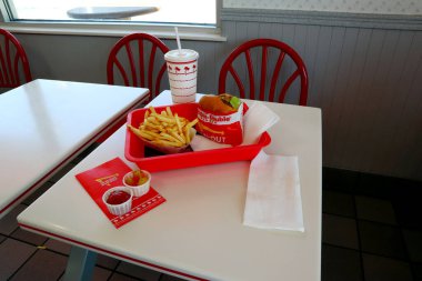 Los Angeles, Kaliforniya 23 Haziran 2023 IN-N-Out Burger, Double-Double Burger ve patates kızartması fast-food restoranının içindeki masada bir tepside.
