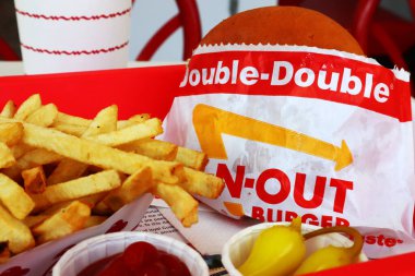 Los Angeles, California - 5 Mayıs 2024 Fast food restoranının içindeki masada yedikten sonra In-N Out Double Burger ve patates kızartması