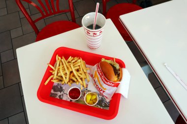 Los Angeles, California - 5 Mayıs 2024 Fast food restoranının içindeki masada yedikten sonra In-N Out Double Burger ve patates kızartması