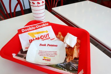 Los Angeles, California - 5 Mayıs 2024 Fast food restoranının içindeki masada yedikten sonra In-N Out Double Burger ve patates kızartması