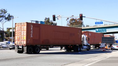 Los Angeles, California - 13 January 2025: Freight Truck carrying a TRITON shipping container on a street toward the Port of Los Angeles in San Pedro clipart