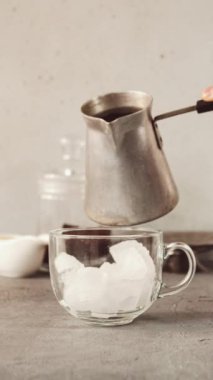 Soğuk kahve hazırlama işlemi. Elleri buzlu cam bardağa kahve ve süt dolduruyordu. Hareket animasyonunu durdur