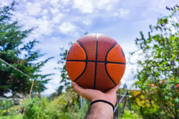 Kumsalda basketbol topunu tutan el.