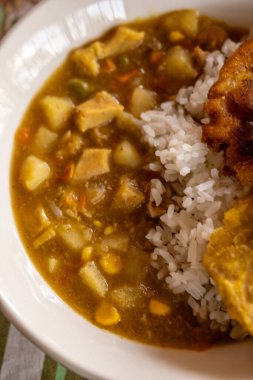 Masada pirinç ve sebzeli bir kase körili tavuk resmi.