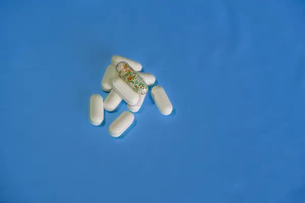 blue pills and capsules. pills on blue background.