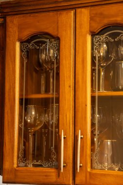 Cam şişeler ve cam bardaklarla dolu eski ahşap mutfak dolabı. yüksek kaliteli fotoğraf