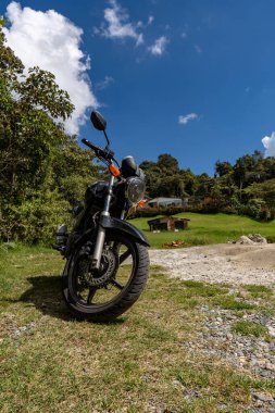 Yolda eski motorsikletiyle gezen bir motosikletli. Güzel Kolombiya manzarası. Seyahat ve motosikletler.