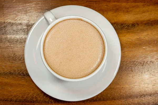 closeup of cup of coffee with milk or cocoa milk with texture and bubbles