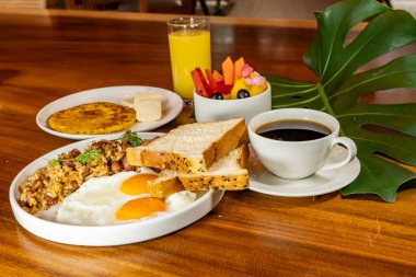Arepas, kahve, ekmek, yumurta, pirinç ve meyveli Kolombiya kahvaltısı.