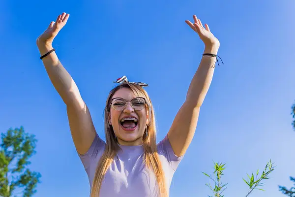 Women Day, March 8, empowered and self-confident woman. Woman expressing leadership and character. Woman happy in nature. Girl with glasses. Girl raising her hands.