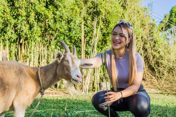 Women Day, March 8, empowered and self-confident woman. Woman expressing comfort and freshness. Happy woman in nature. Girl with glasses. Woman petting a goat.