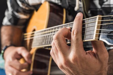 Latin bir adam odasında akustik gitar çalıyor. Ahenkli enstrümanlı bir müzisyen..