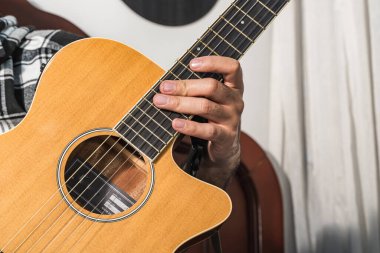 Kolombiyalı bir adam odasında gitar çalıp öğreniyor. Akustik ve harmonik enstrüman.