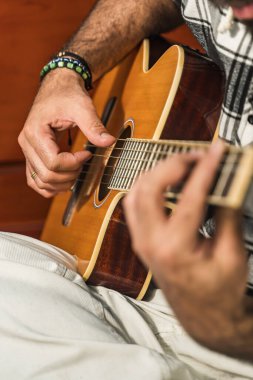 Kolombiyalı bir adam odasında gitar çalıp öğreniyor. Akustik ve harmonik enstrüman.