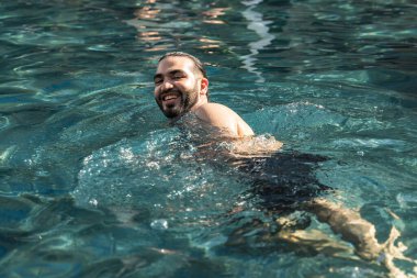 Yazın havuzda yüzen aktif bir adam, serin ve çok mutlu. Yaşam tarzı ve egzersizi.