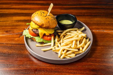 Ahşap masadaki otel restoranında patates kızartmalı leziz hamburger. Çok lezzetli yemekler. Gastronomi.