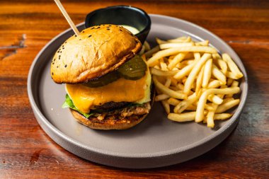 Ahşap masadaki otel restoranında patates kızartmalı leziz hamburger. Çok lezzetli yemekler. Gastronomi.