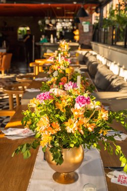 Otelin çatısında güzel ve zarif bir masa. Çiçekler, günbatımı ve zarafet.