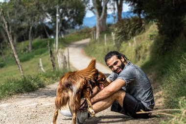 Yetişkin bir melez, kırsal kesimdeki çoban köpeğine sevgiyle gülümsüyor.